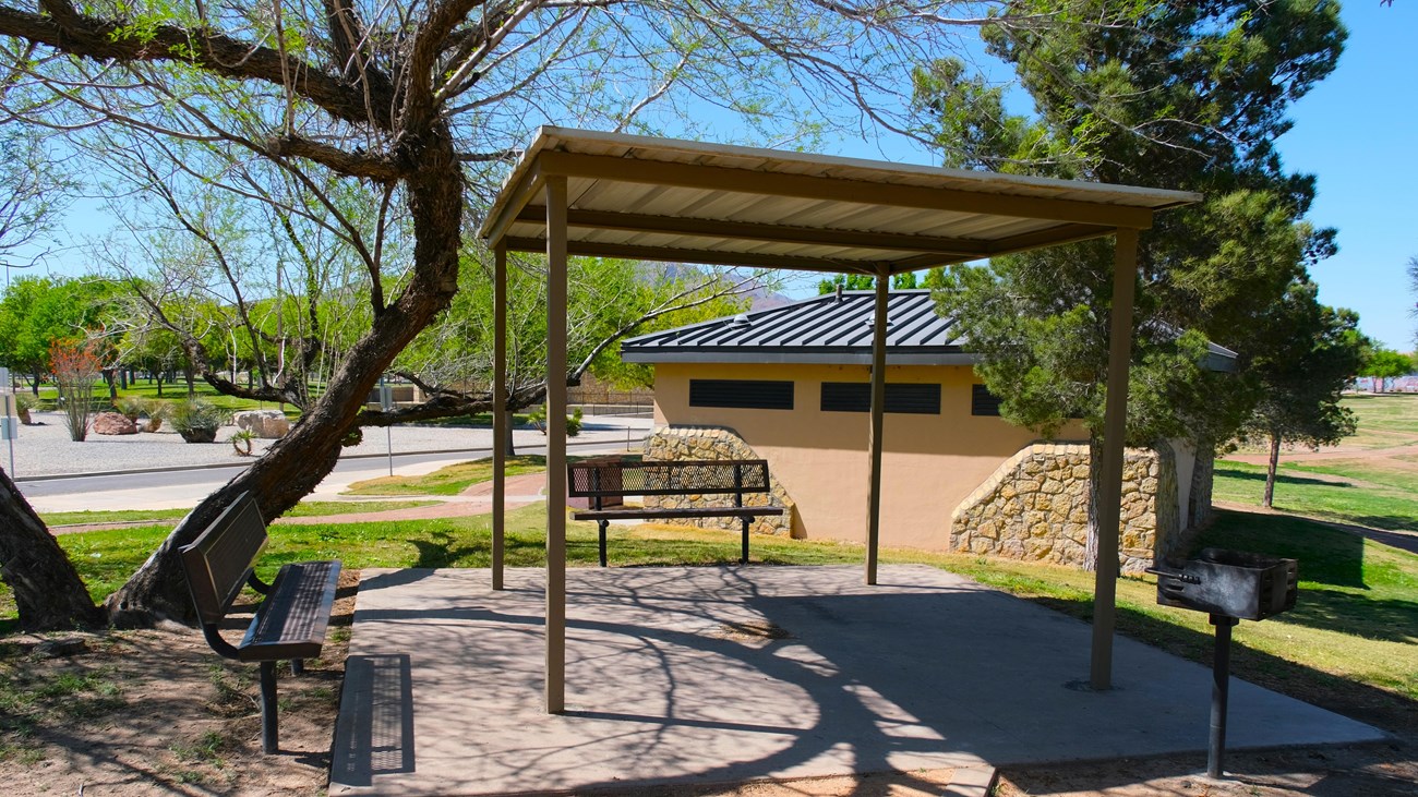 A covered picnic shelter with landscaping and comfort station behind