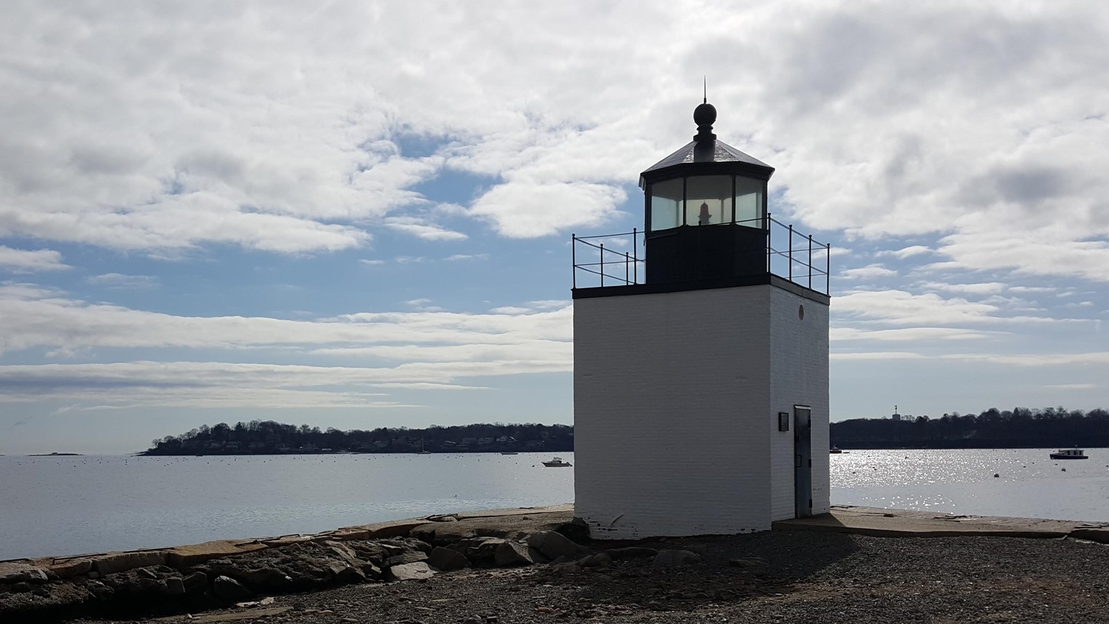 White lighthouse 12 feet square and 20 feet tall with red flashing light with water on 3 sides