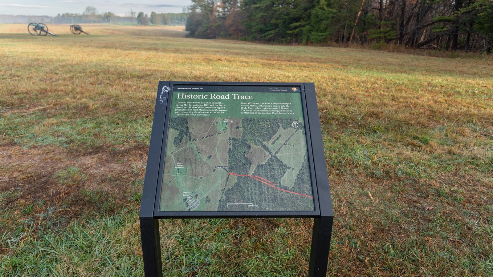 An informational panel in front of a grassy field.