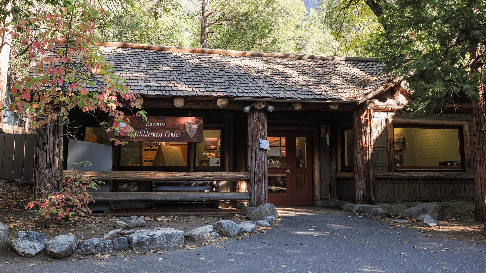 A rustic brown building with large beams and posts, a shingled roof top and shingled siding