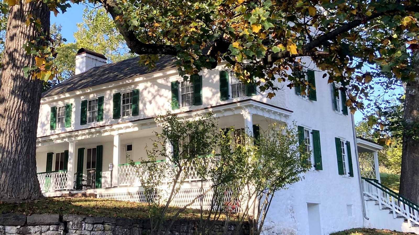 A large, white home with three floors and two porches. 