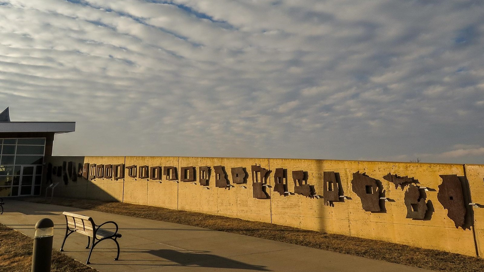 A concrete wall with metal cut outs of the homesteading states.