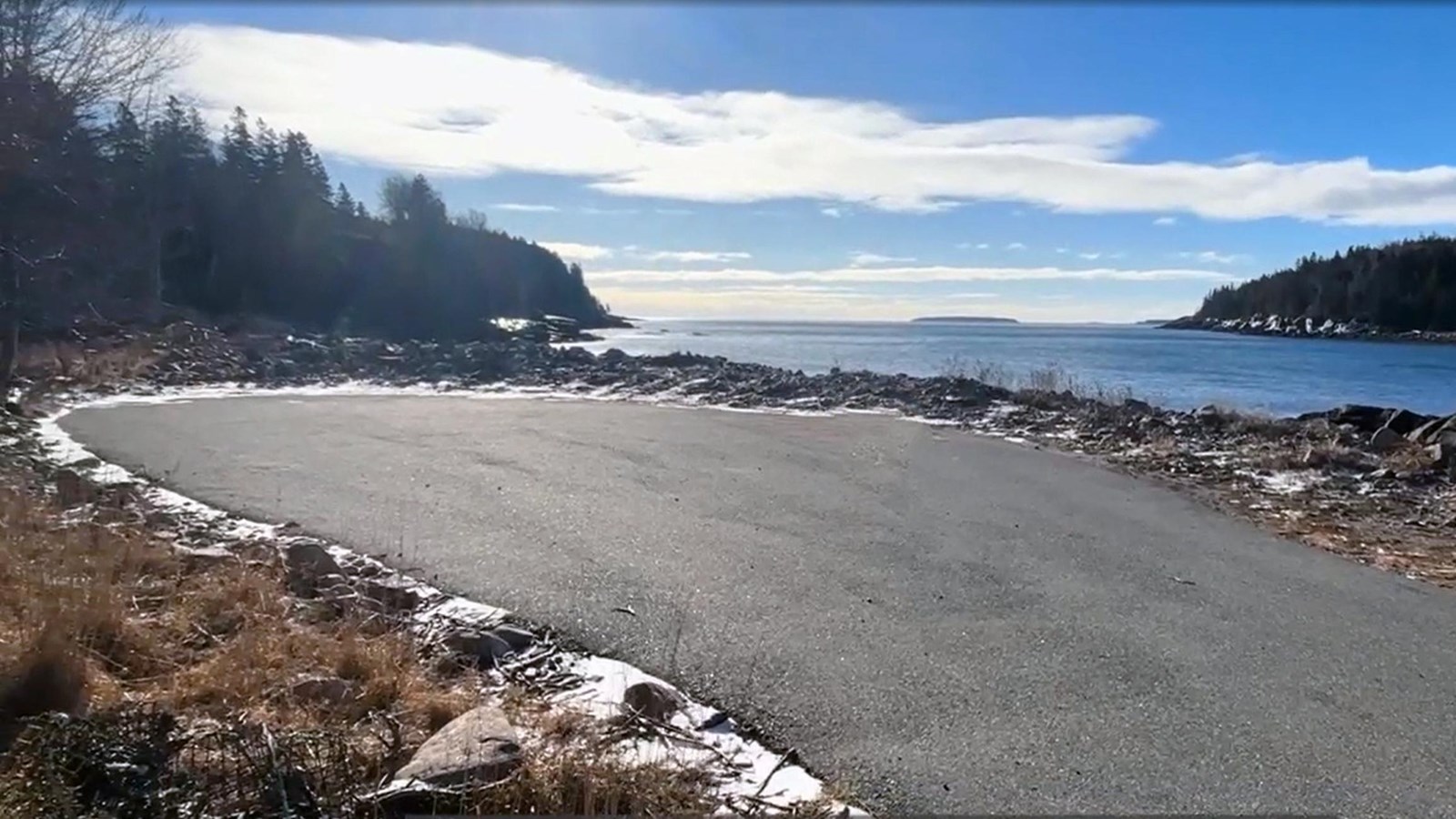 Small asphalt parking area nestled along a rocky shoreline.