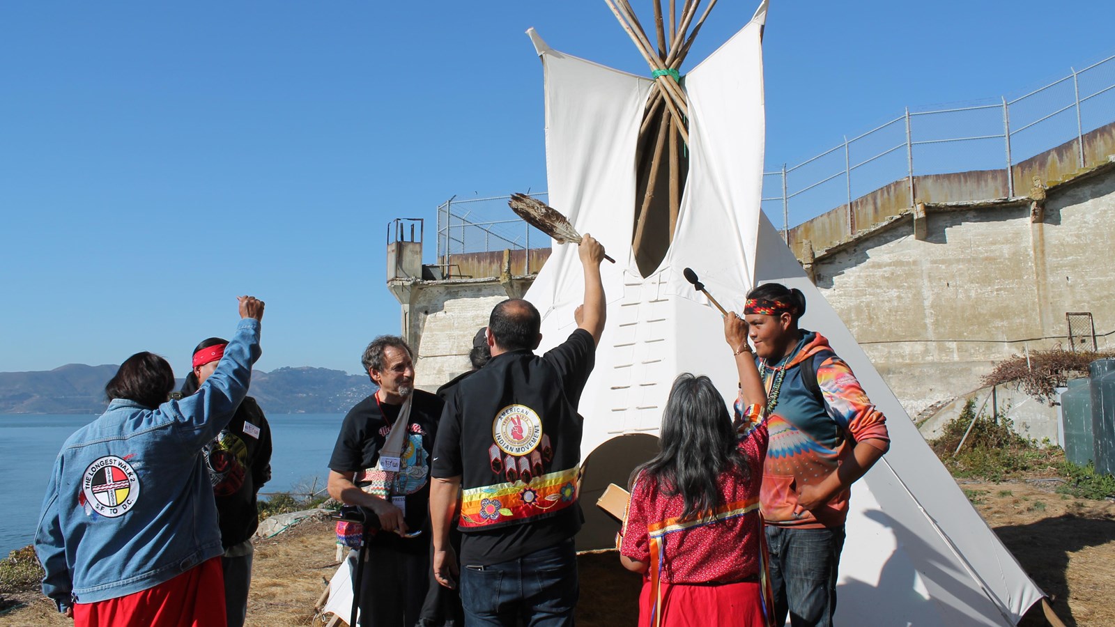 Colored photograph of the recreated tipi from 2019 surrounded by Native American youth.
