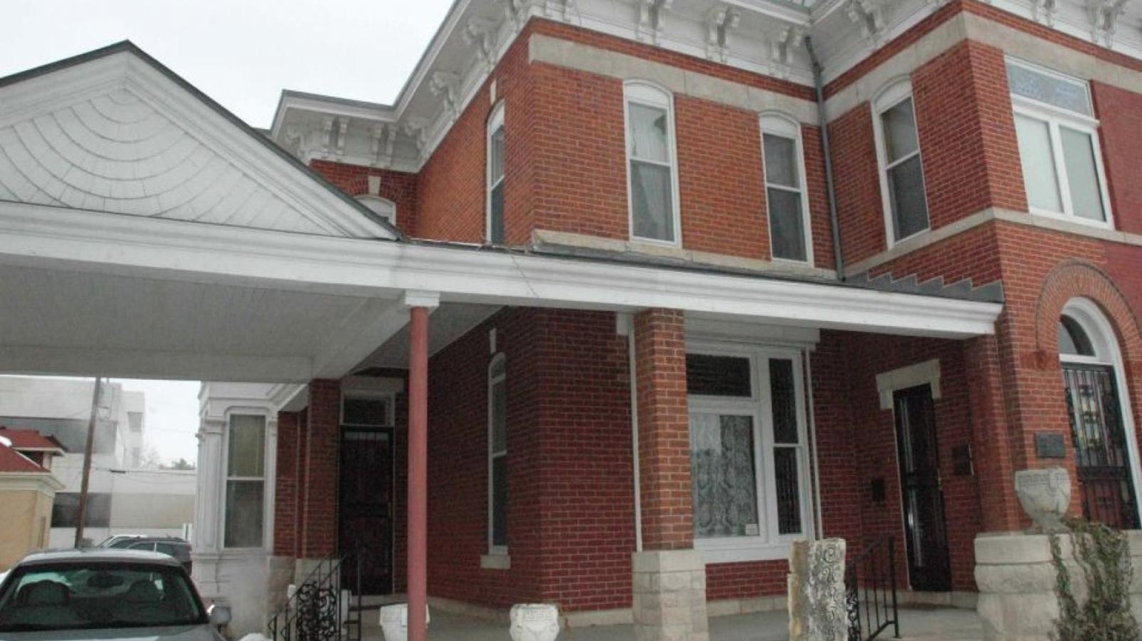 A two-story red brick building with a stone wall at the front of the house.