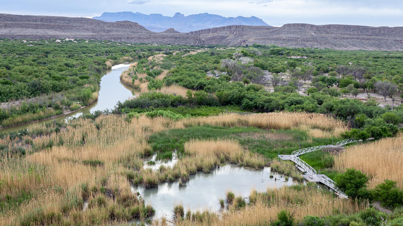 A view from a high point looks out over the Rio Grande, the wetland, and the Chisos Mountains.