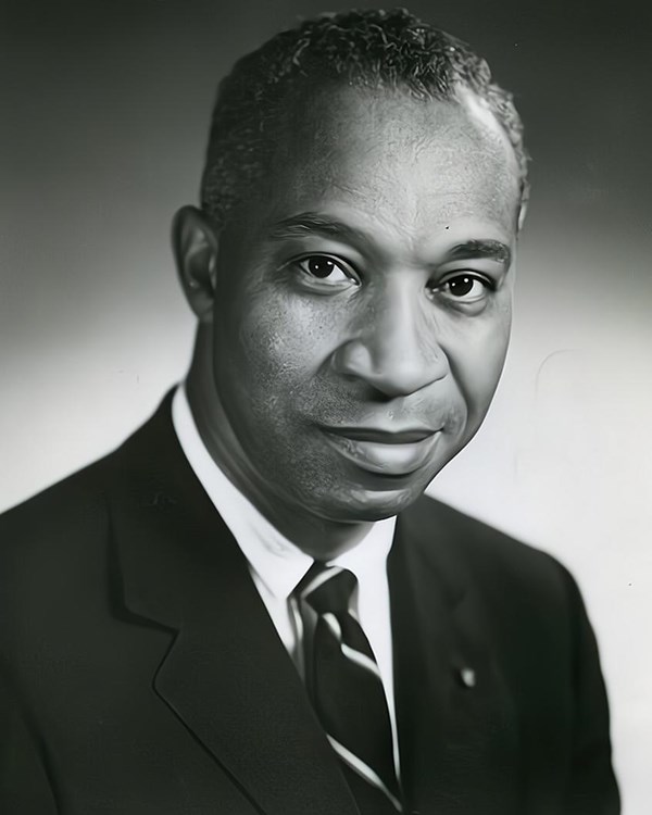 A black and white image of a man wearing a sport coat and tie