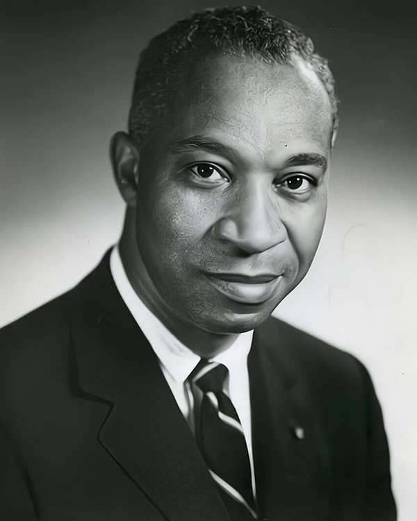 A black and white image of a man wearing a sport coat and tie