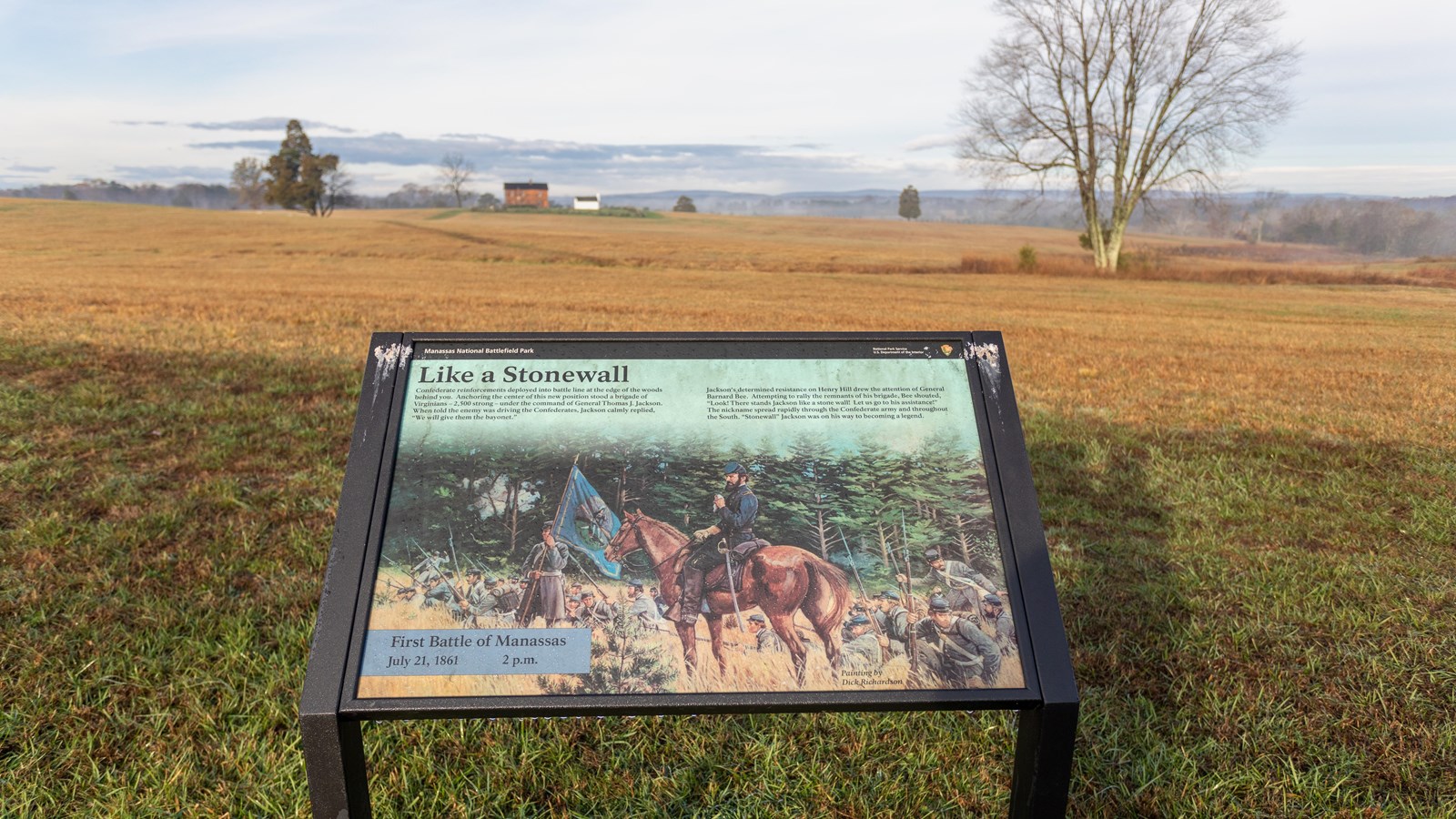 An informational panel in front of a grassy field. 