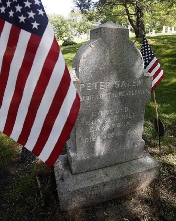 Peter Salem gravestone with American flag stuck in the ground next to it.