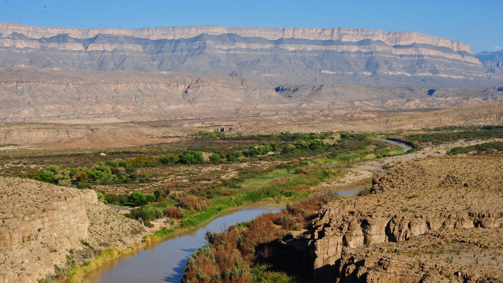 The Rio Grande flows around a bend beneath the imposing cliffs of the Sierra del Carmen.