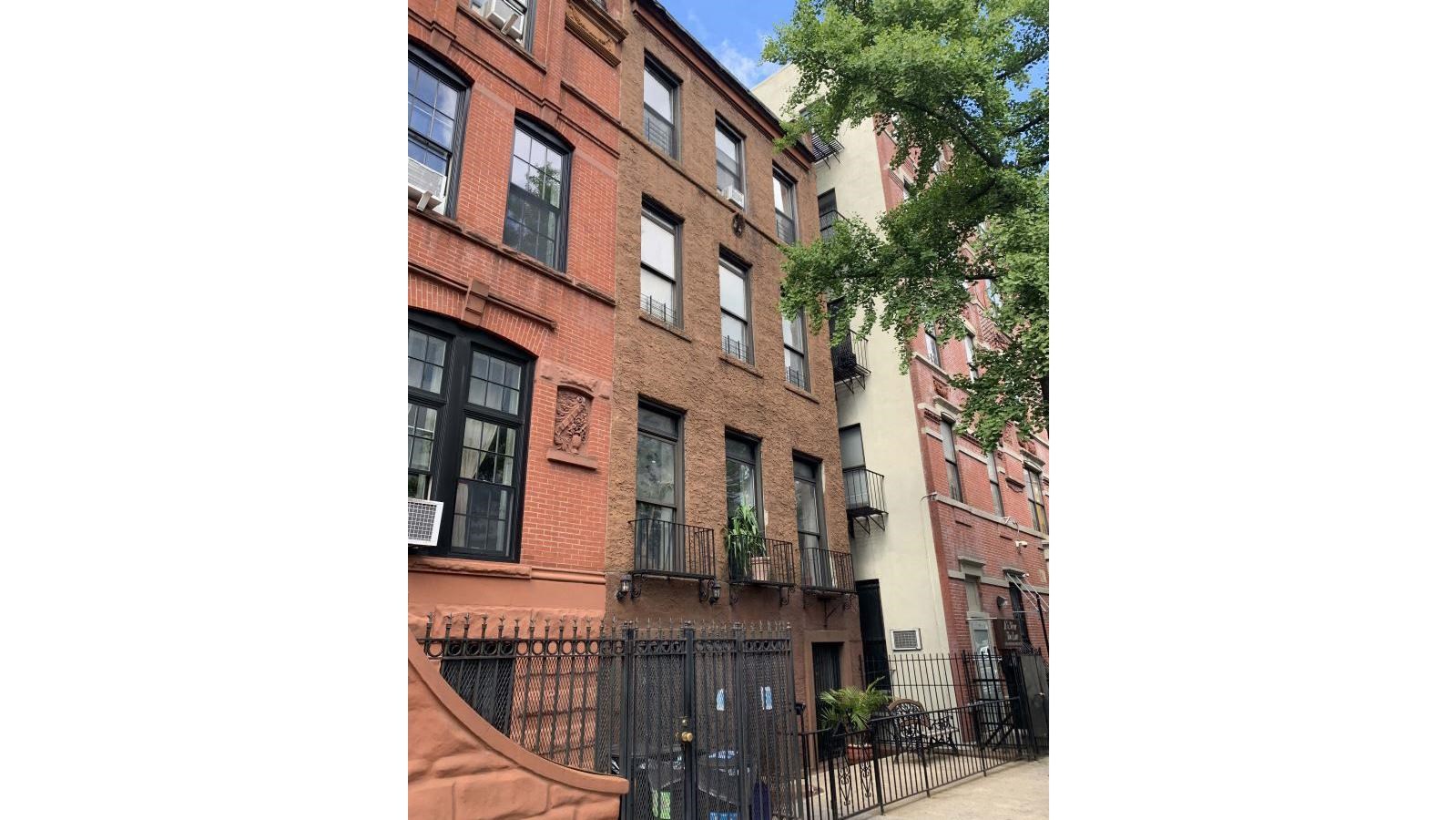 four story apartment building with three bay metal windows balconies on the second floor. 