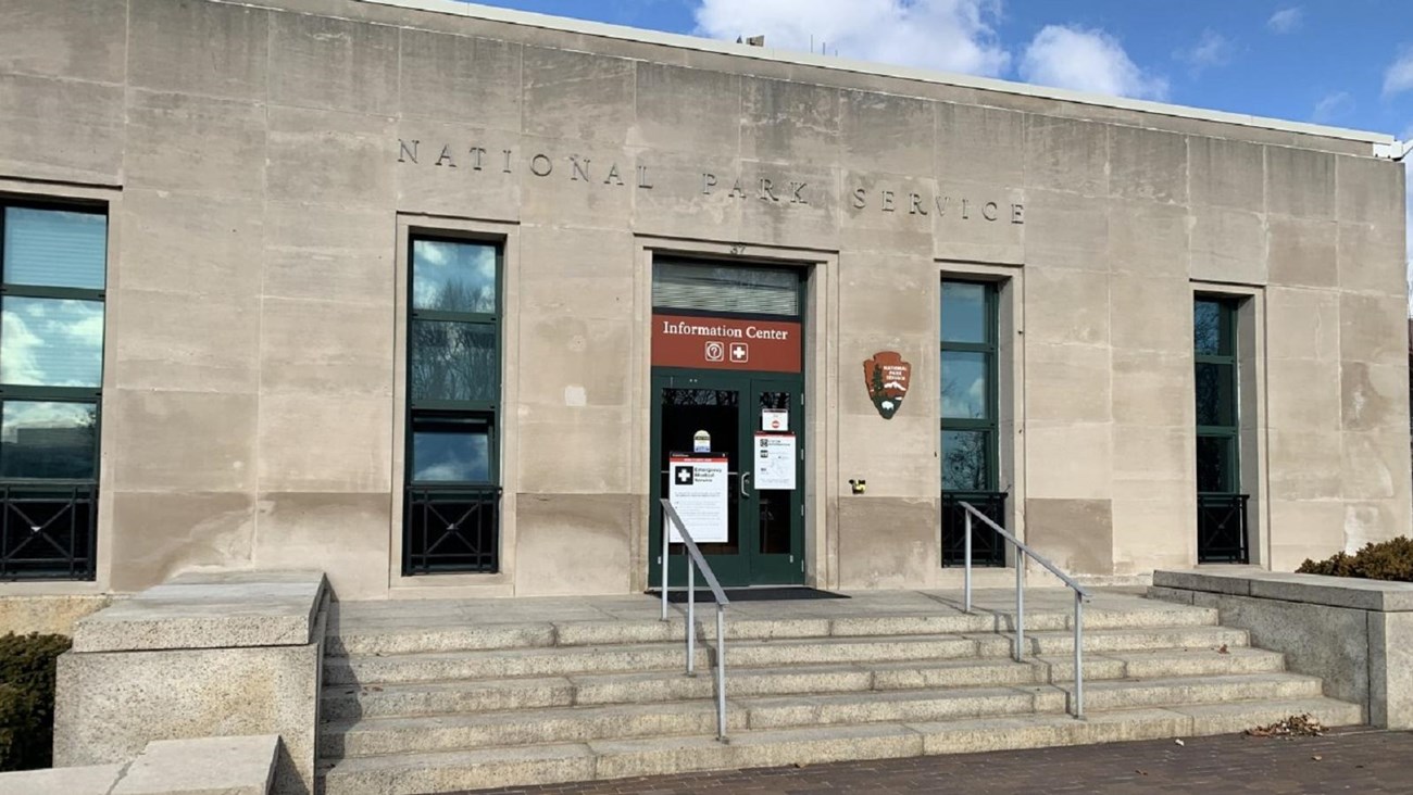 The Information Center on Liberty Island is a concrete building with a few steps leading up to it. 