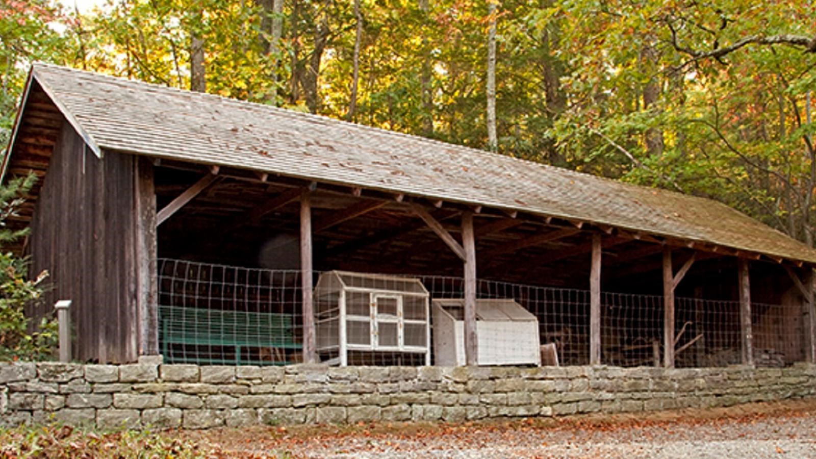 An open front wood shed used as storage for farm supplies