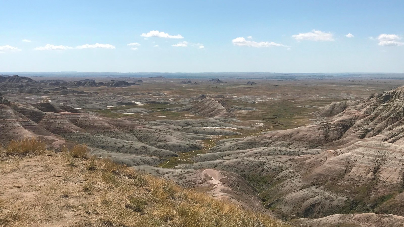 A drop-off into a vast Badlands landscape extending miles into the horizon.