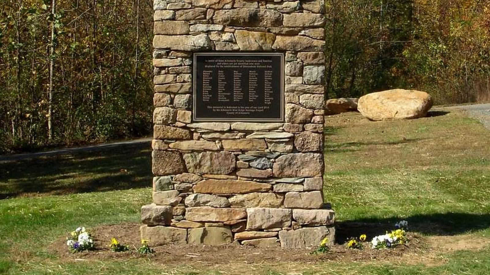 A large replica sandstone chimney features a bronze plaque bearing the sur names of families.