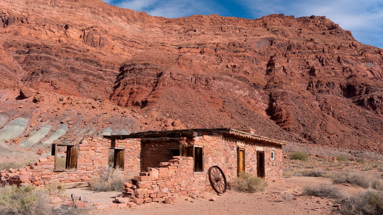 Single story, long two-room stone building with a log roof. Building in varying stages of collapse.
