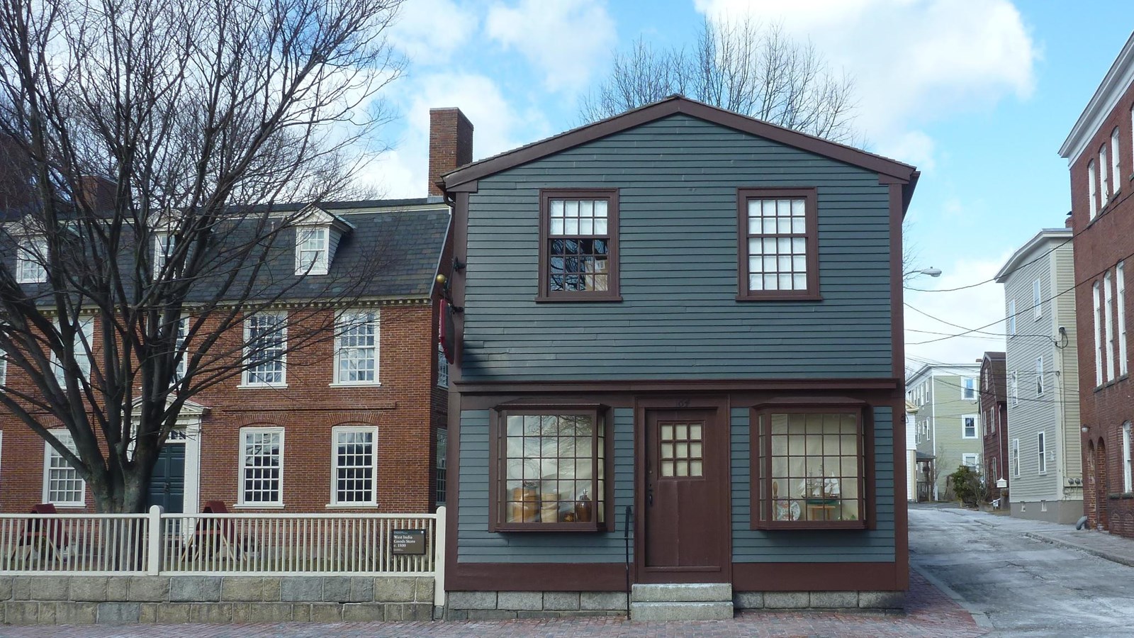 Blue two story building with maroon trim and two windows on each floor facing the street