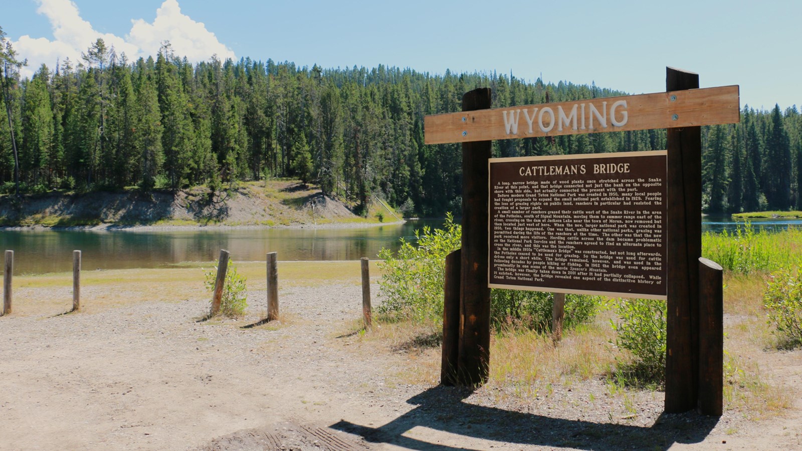 An informational log sign explains the history in front of the Snake River.