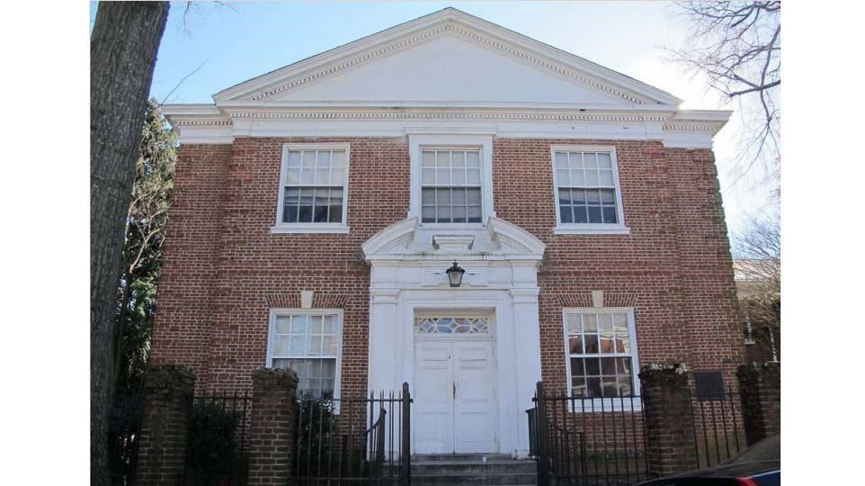 two story brick building with a white rooftop, and 5 windows surrounding the French door entrance.  