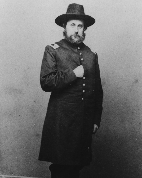 Portrait of Theron E. Hall, standing, with his hand tucked into his coat, during the Civil War