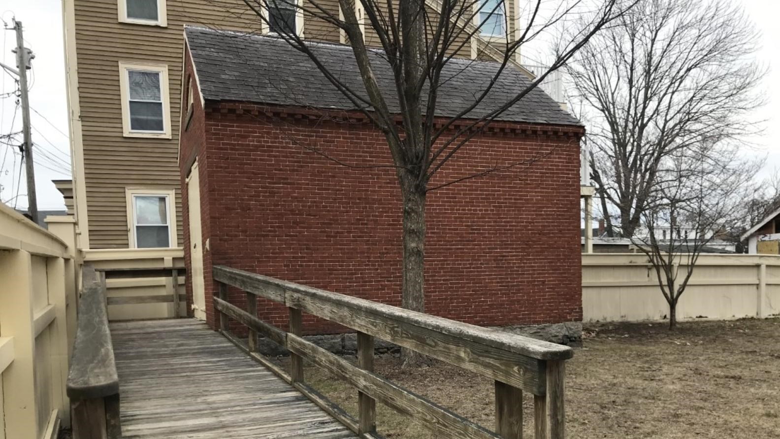 A one-story, rectangular brick building with wooden ramp leading to entrance