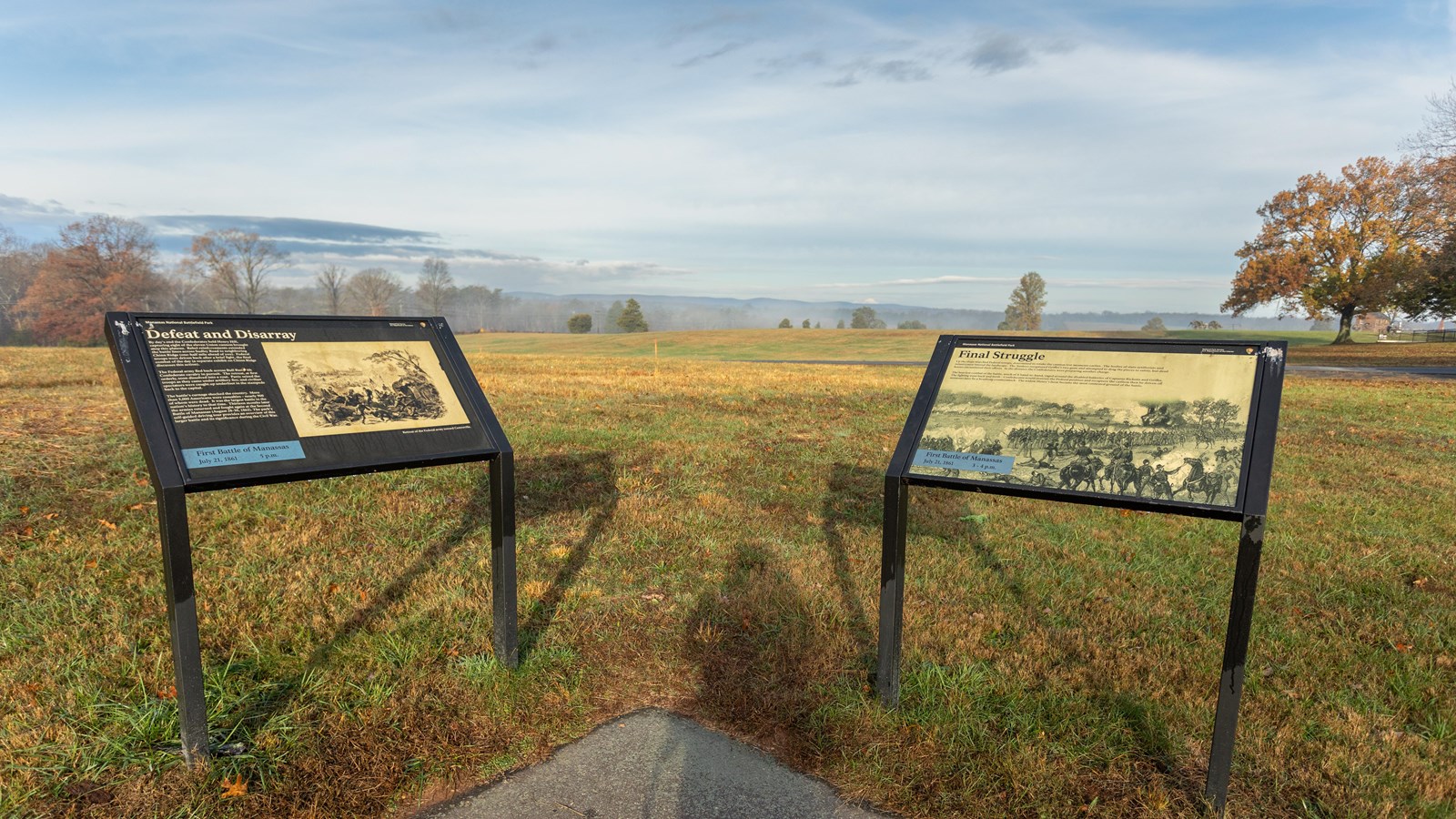 An informational panel in front of a grassy field. 
