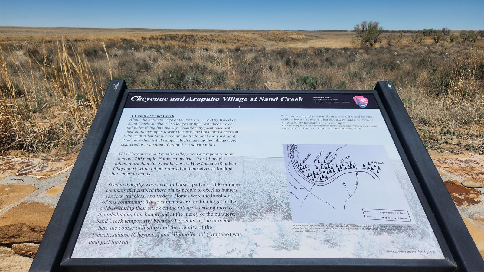 A wayside in a stone base. Beyond it is a bluff line descending into a valley.