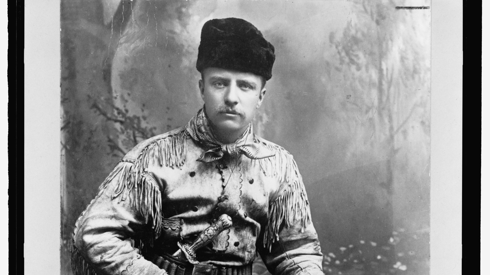 Theodore Roosevelt in a buckskin hunting sui with a rifle