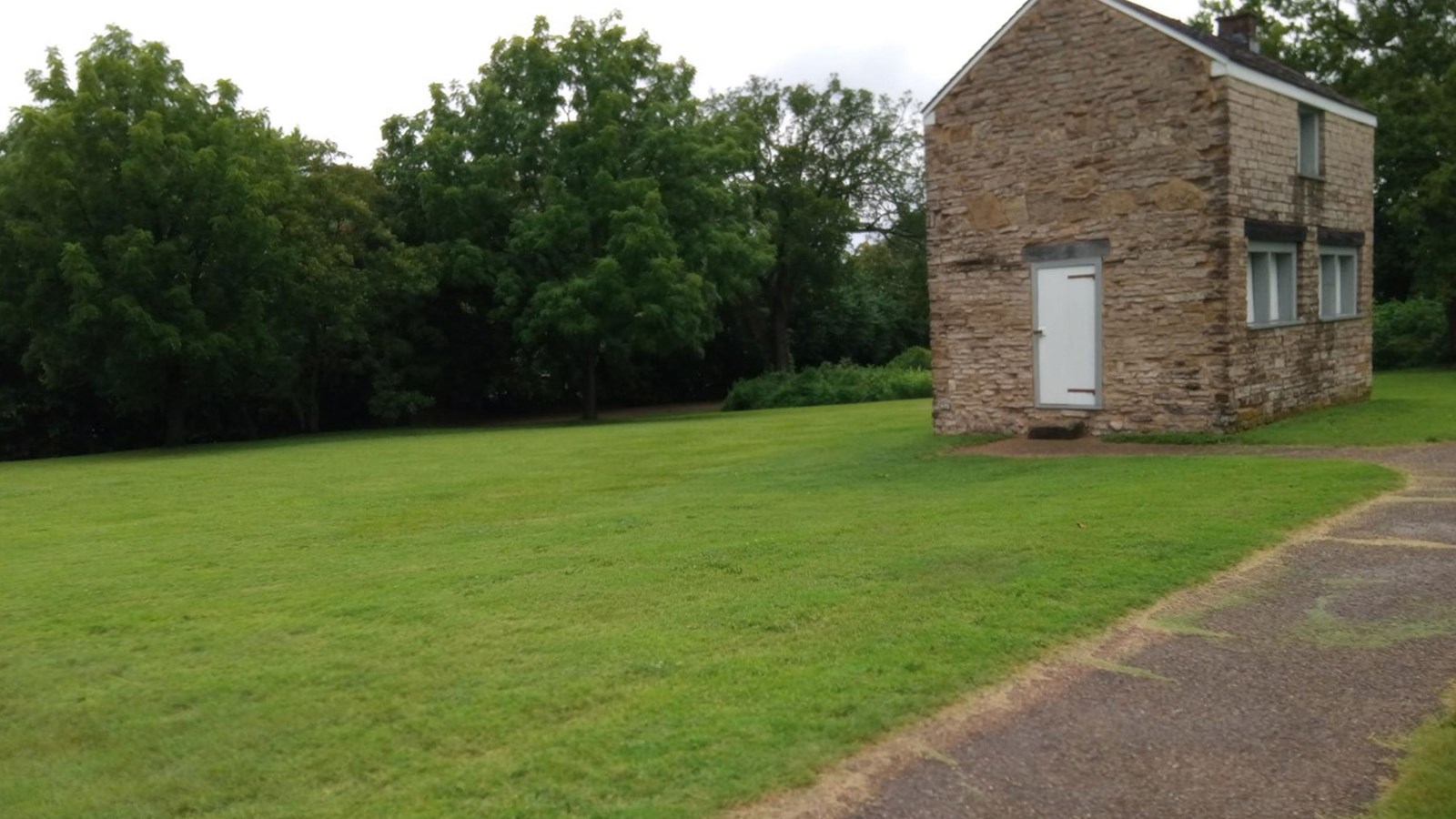 one story stone building next to large grassy area