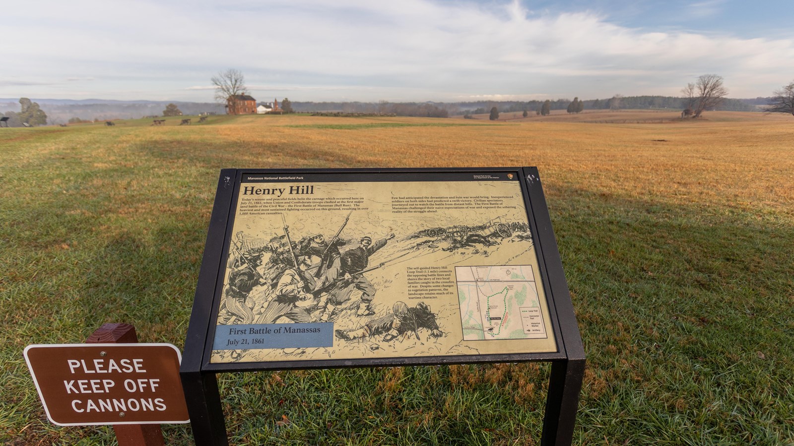 An informational panel in front of a grassy field. 