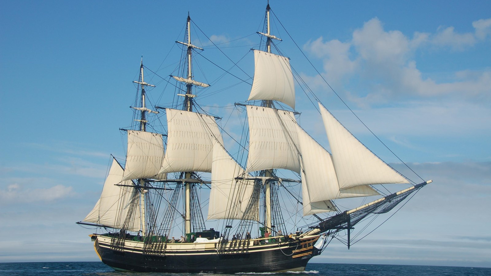 A two-decked, three-masted merchant ship sailing the seas on a sunny day