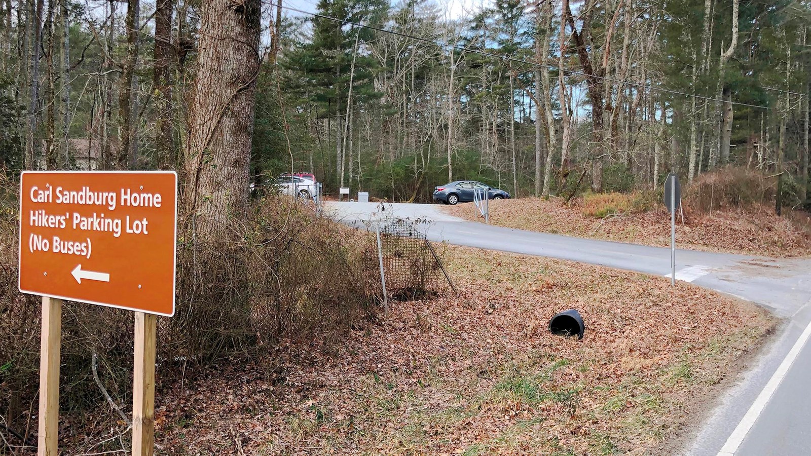 View of entrance to hikers\' parking lot with directional sign and driveway.