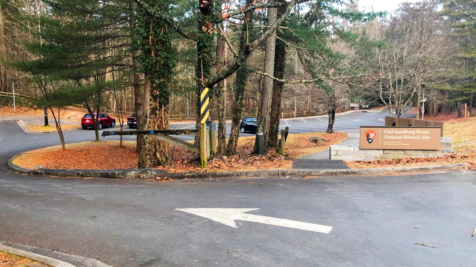 View of entrance to main visitor parking lot with driveway and parking spaces.