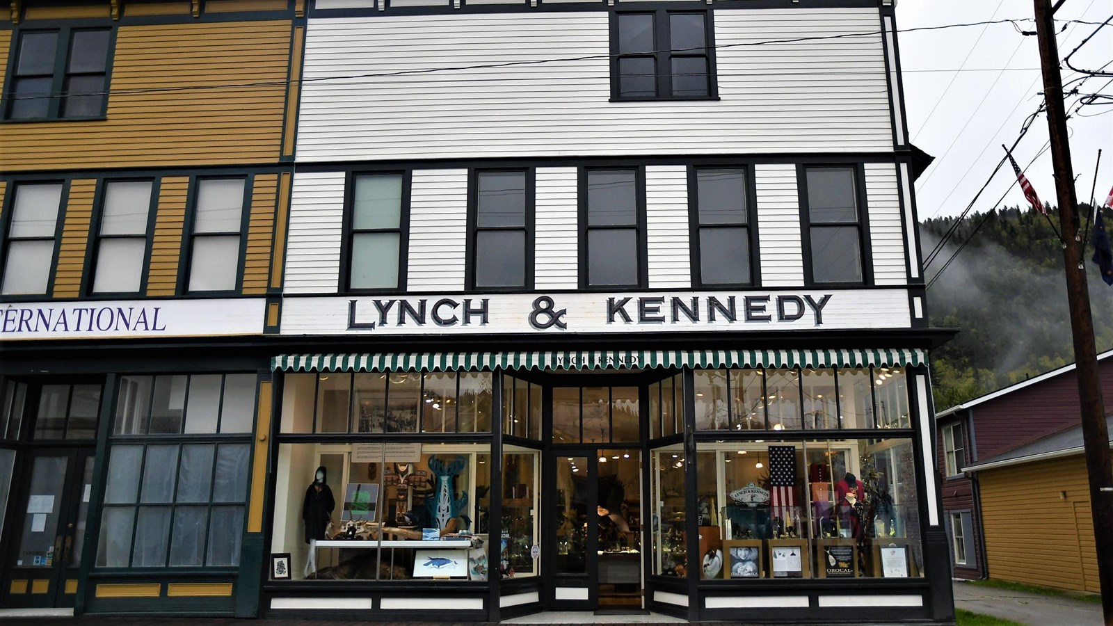 A two-and-a-half story white building with green trim reads “Lynch & Kennedy”.