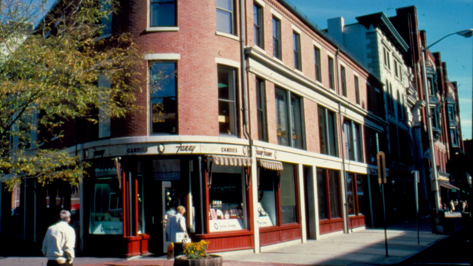 A rounded corner of a three story tall brick building at a street corner.