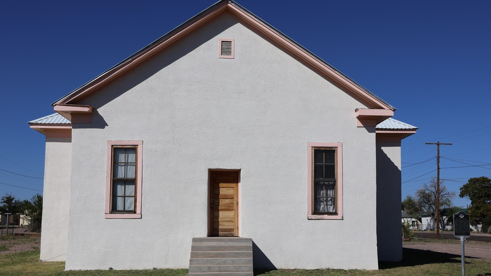 plain house with two small windows on either side of the centered door. Steps lead up to the door