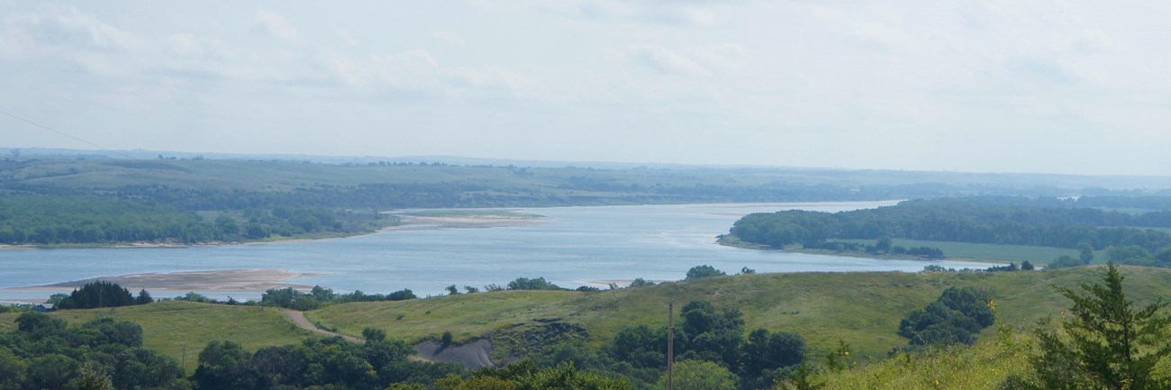 Overlooking the Missouri River containing sandbars and trees along the banks. The river bends right.