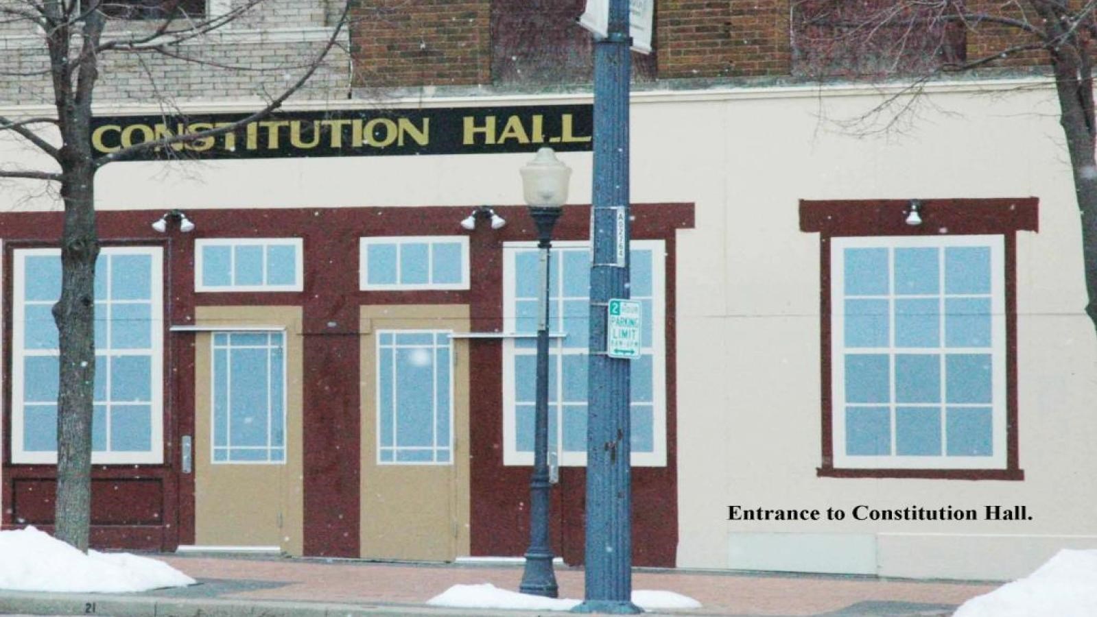 Double doors and three windows can be seen at the front entrance of this building.