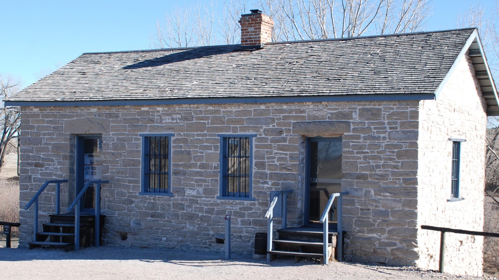 A stone building with two doors and a lower level.
