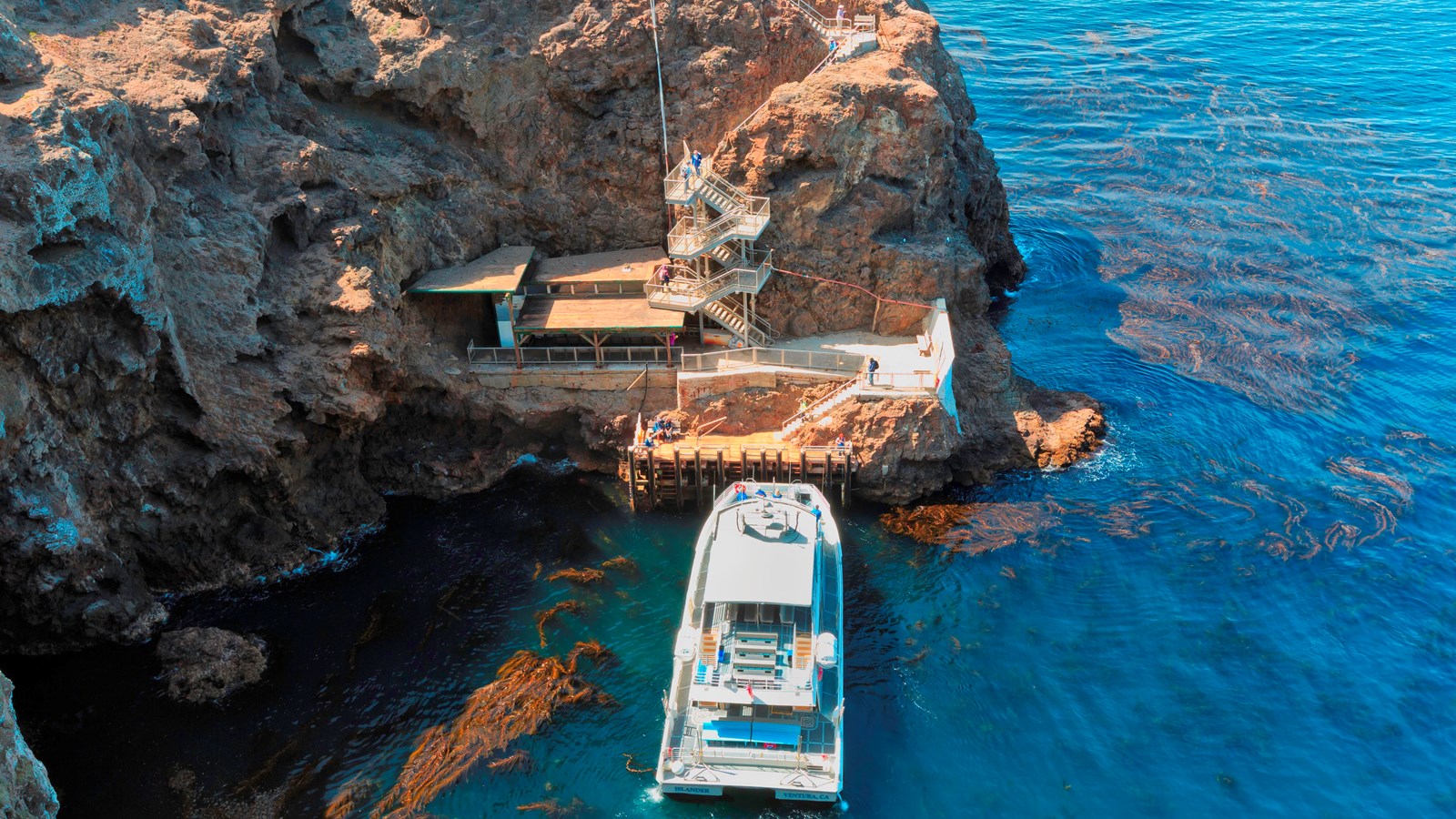 Steep cliff with boat, white sea wall and stairs leading to the top.