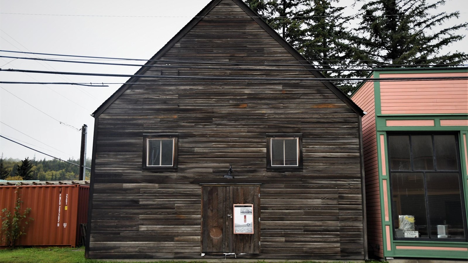 A three-story unpainted wood building with a gable roof.