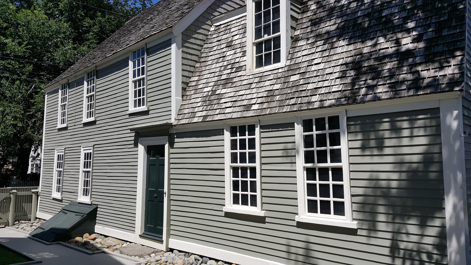 Two-story rectangular house with light green siding and white trimmed windows