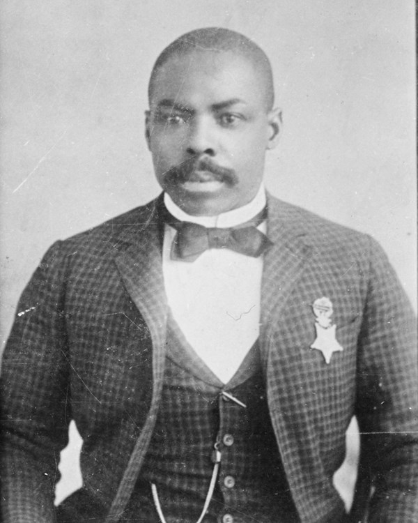 Black and white photograph of African American man in suite of late 1800s wearing Medal of Honor