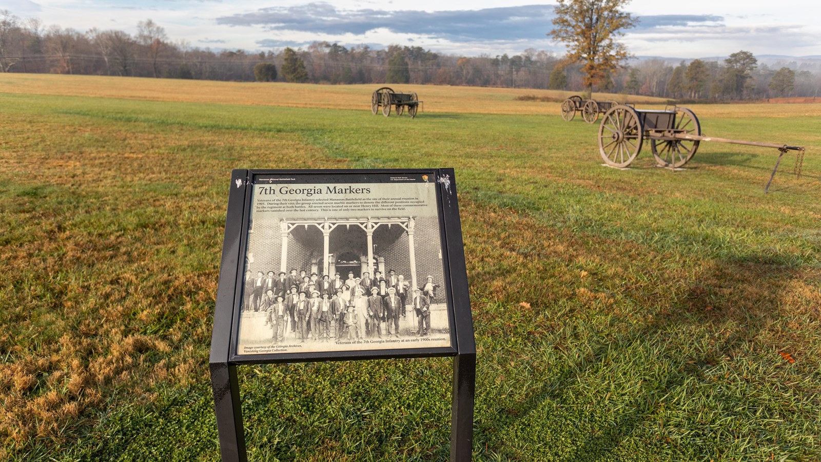 An informational panel in front of a grassy field. 