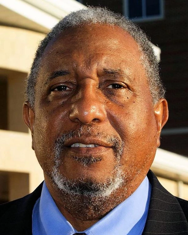 An older black man smiles for a photo.