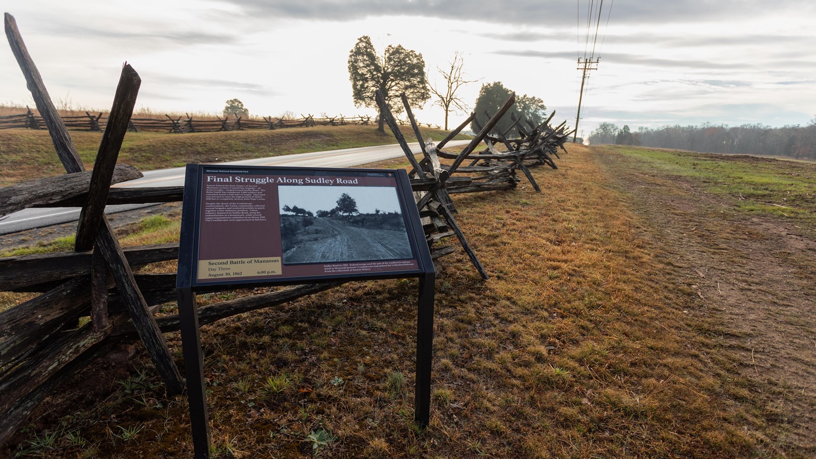 An informational panel in front of a wooden fence 