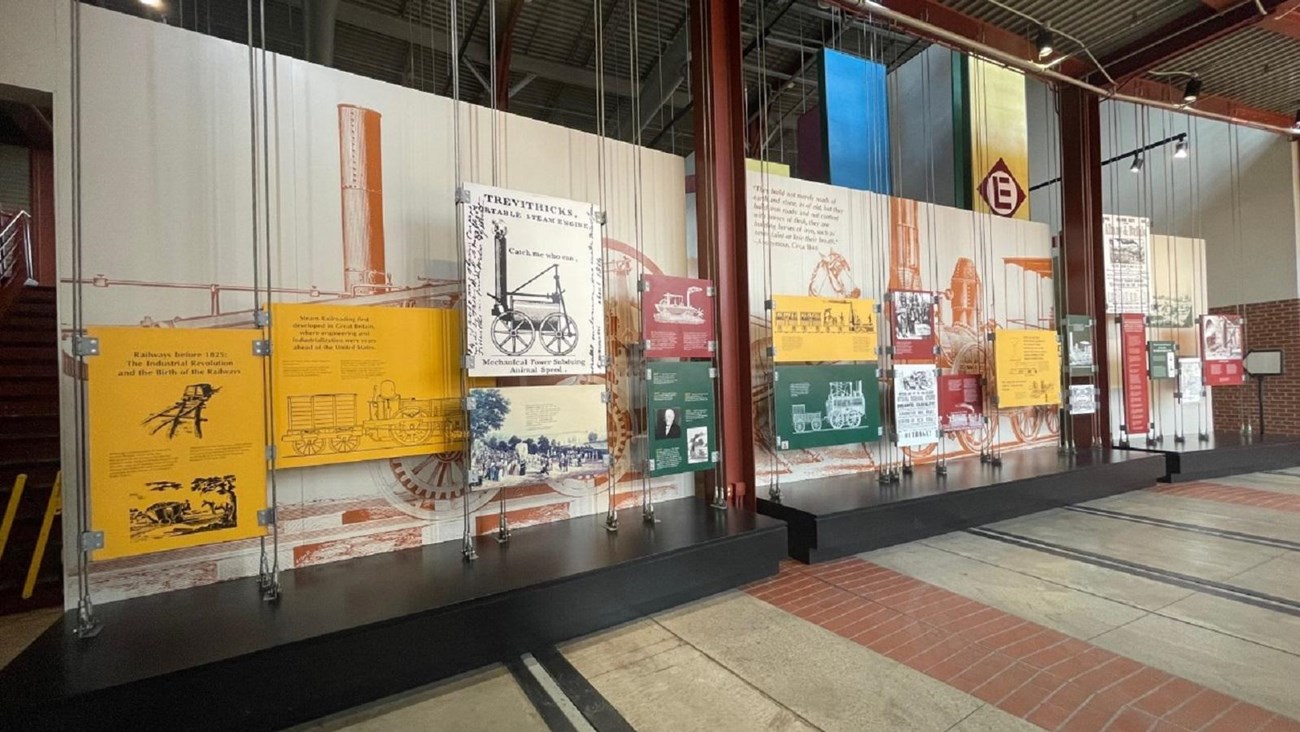 Entryway of museum corridor with exhibit panels suspended from the ceiling