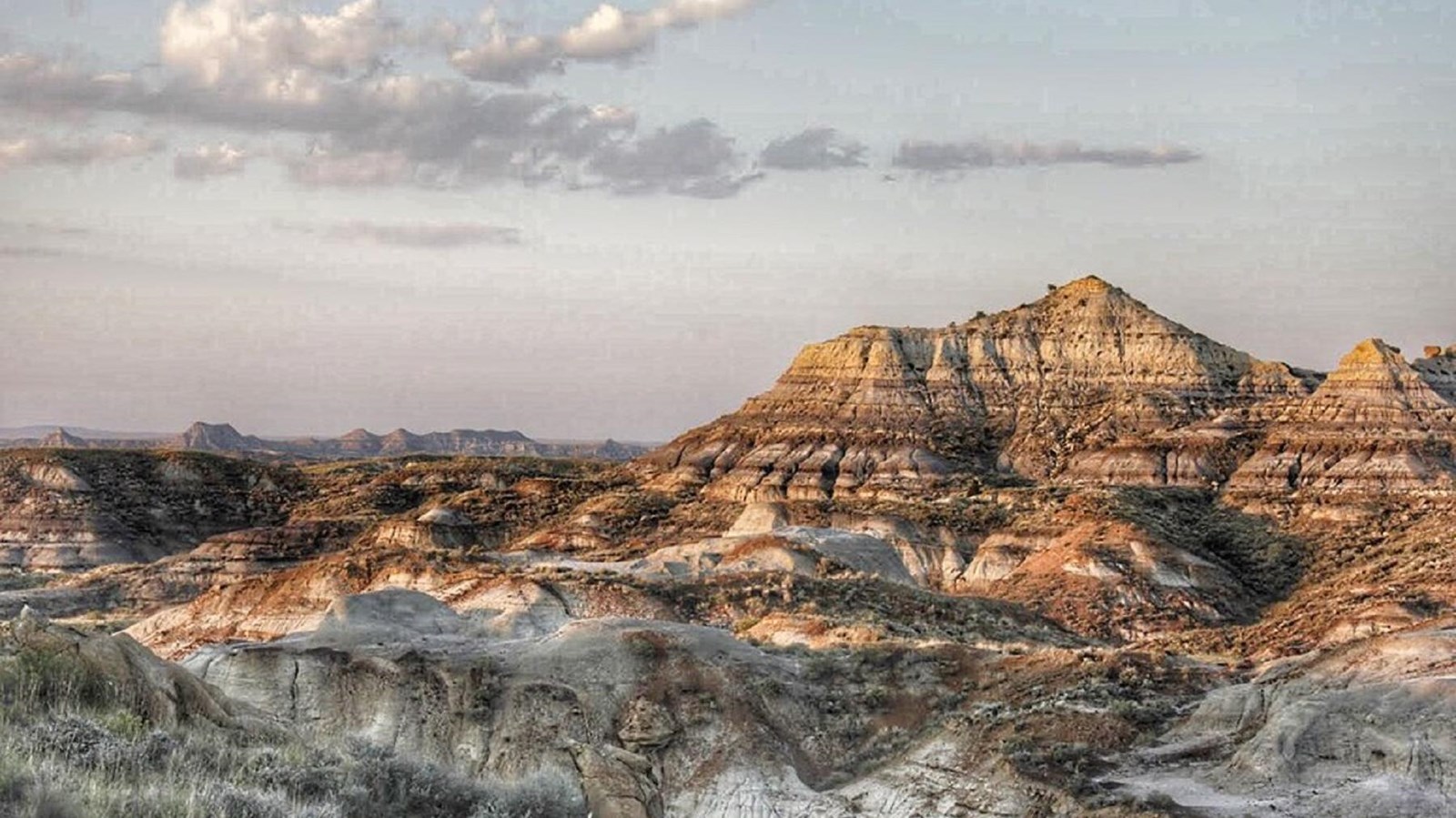 Banded hills and bluffs lit by a setting sun
