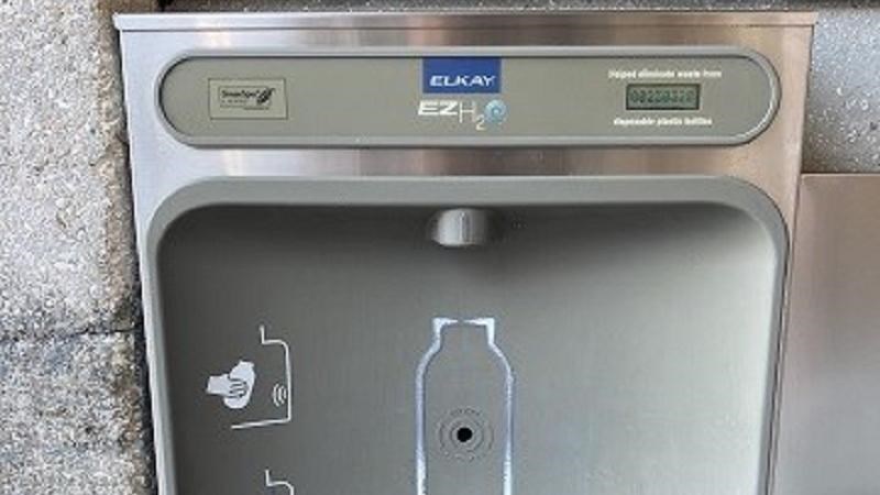 A water bottle refill station is located under the stone arch, outside the restrooms